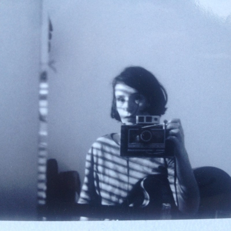 a woman taking a photo of herself in the mirror using a polaroid