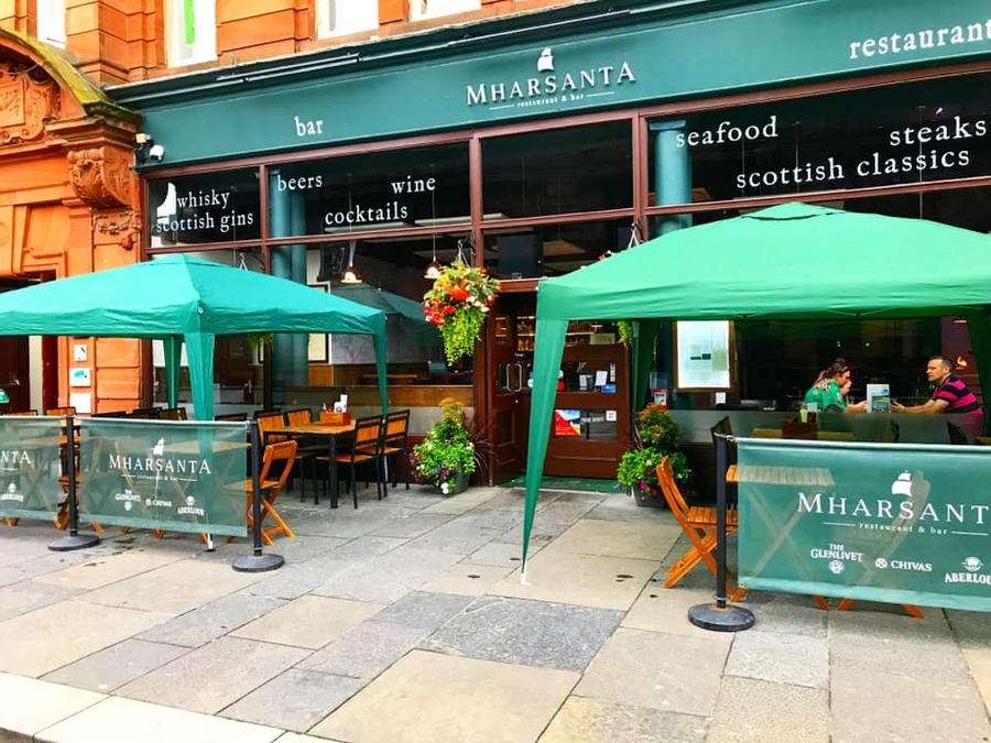 Mharsanta exterior a group of people sitting at a table with a green umbrella