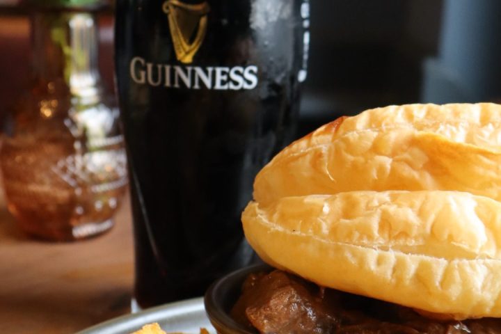 Pint of Guinness with steak pie and chips on a table setting.
